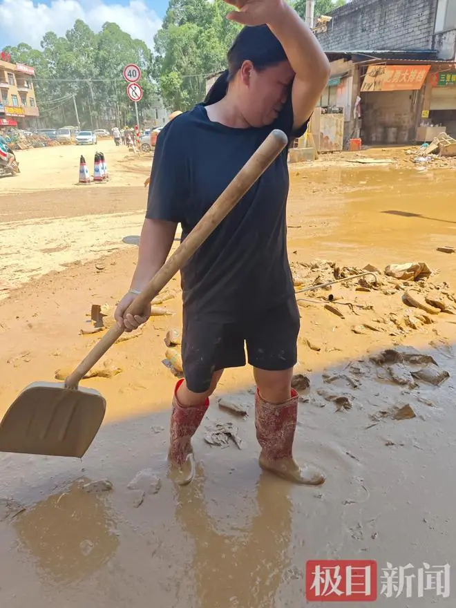 贵港一农资店女老板忙着清理淤泥,说起巨大的损失,还有三个孩子要读书,已经忙碌三天的她哭了