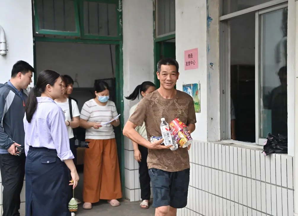 7月8日,在广西贵港市覃塘区覃塘三中安置点,受灾群众领取生活物资。新华社记者 周华 摄